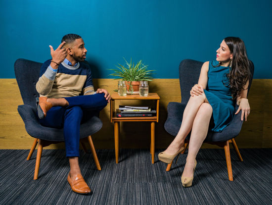 two people sitting side by side with small table between them