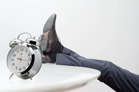 man resting his legs on table with a clock