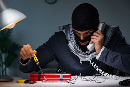 masked person on phone while looking at bomb components