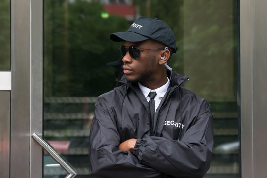 man in a security jacket standing with crossed arms